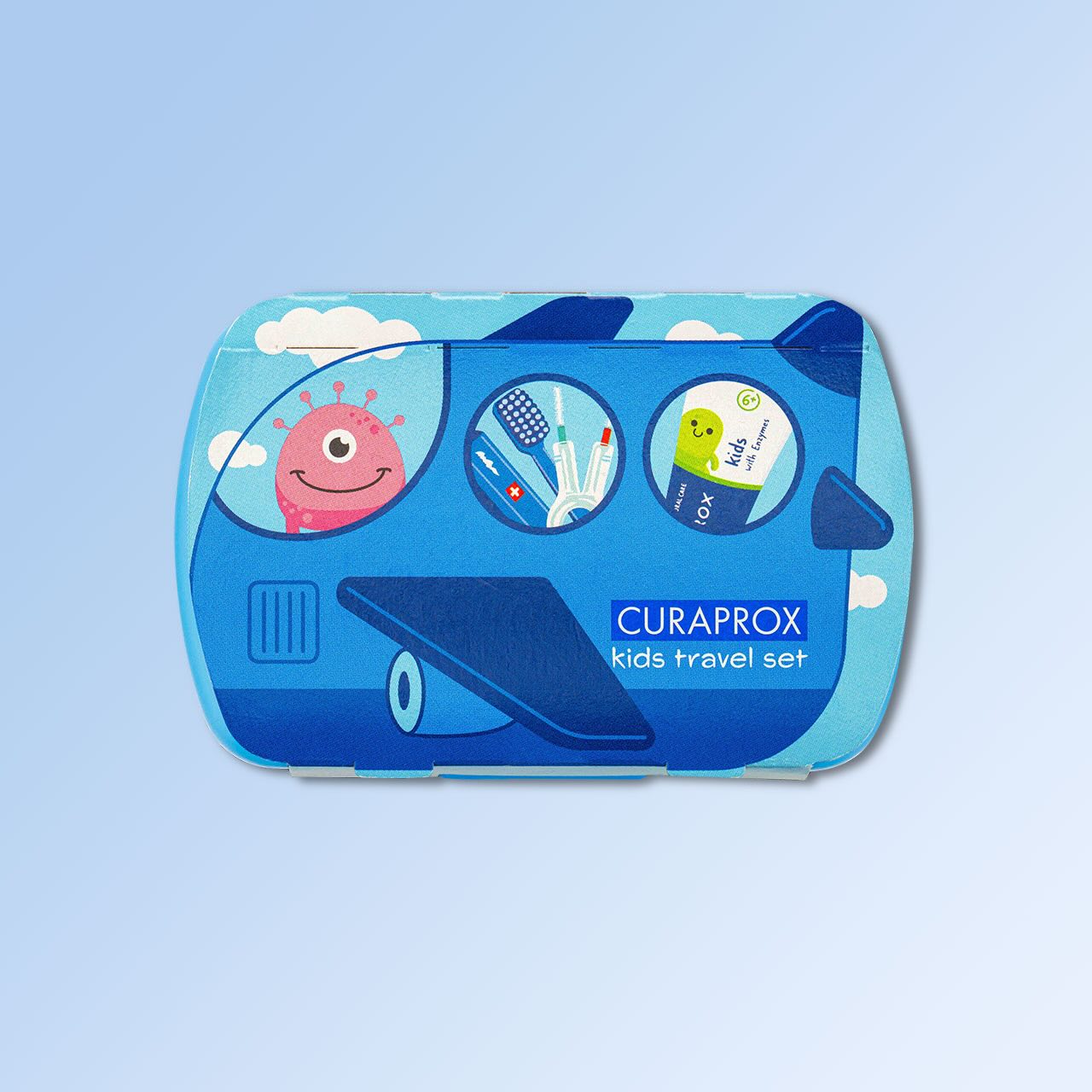 Ein blaues Kids Travel Set, die Banderole zeigt das Flugzeug-Motiv. Aus dem vorderen Fenster schaut ein grünes Fantasiewesen, im mittleren Fenster sind Teile der geteilten Handzahnbürste und