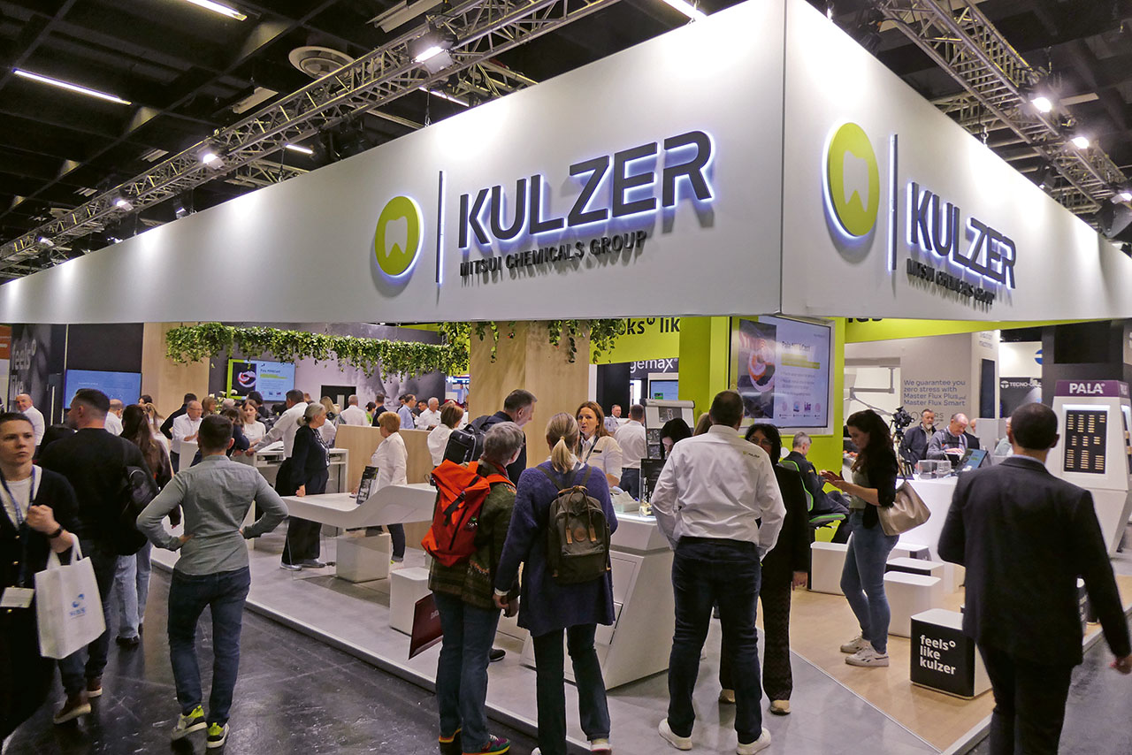 Ein Messestand der Dentalfirma Kulzer, Messebesuchende im Vordergrund.