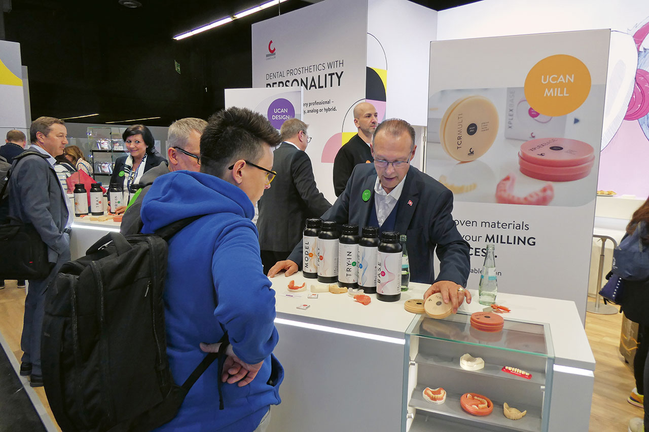 Ein Besucher lässt sich von einem Standmitarbeiter am Messestand dentale Materialien und Ronden zeigen.