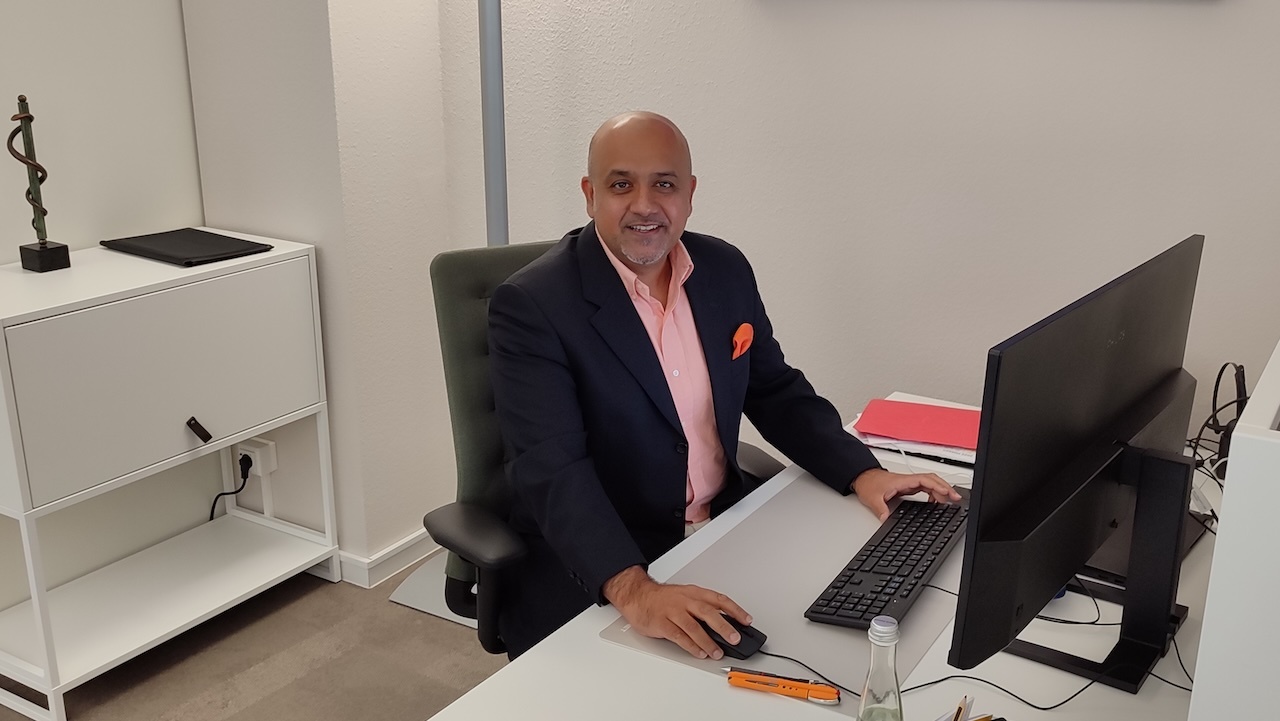 Muzafar Bajwa MSc, LZKH-Vorstandsmitglied der LZKH und einer der wissenschaftlichen Leiter des Hessischen Zahnärztetags, sitzt an seinem Schreibtisch vor einem Computer und schaut in die Kamera.