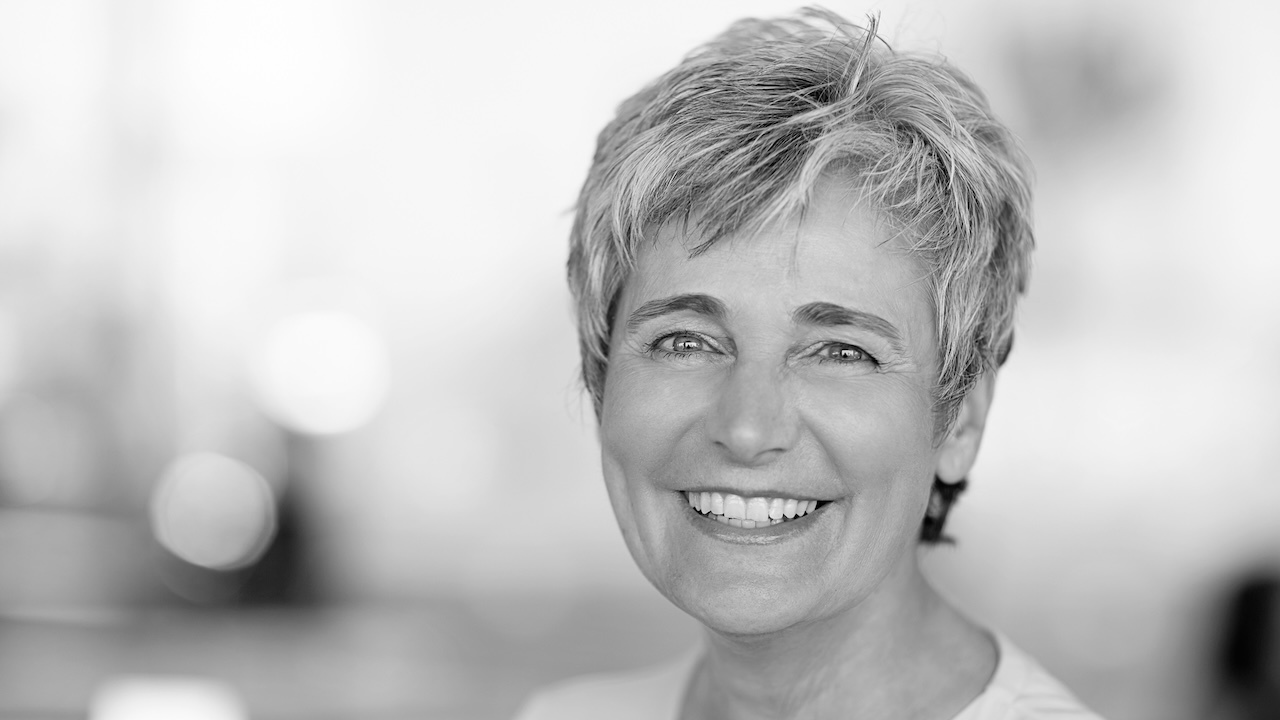Schwarz-Weißbild einer lächelnden Frau mit kurzen grauen Haaren.