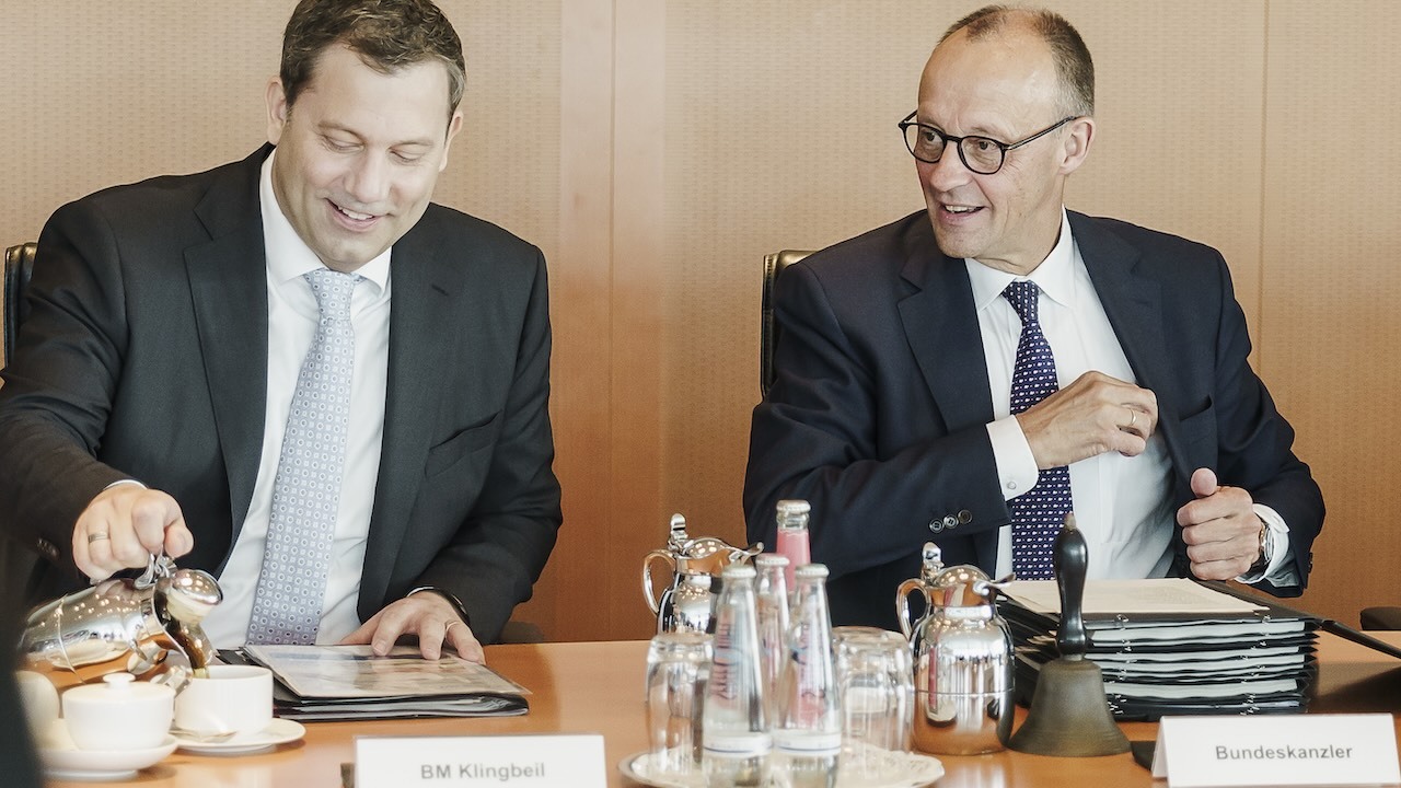 Bundesfinanzminister Lars Klingbeil (SPD, links) und Bundeskanzler Friedrich Merz (CDU) sitzen gut gelaunt am Kabinettstisch.