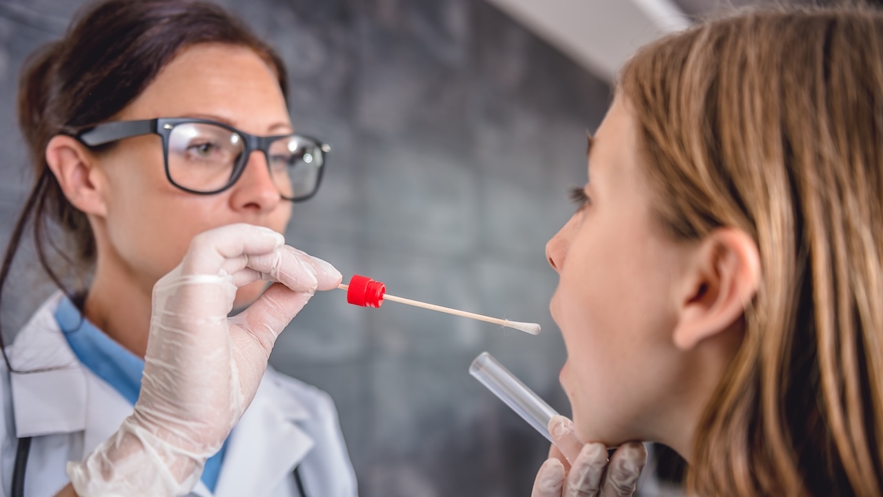 Ärztin mit Brille (links) nimmt Speichelprobe bei einer Patientin (rechts).